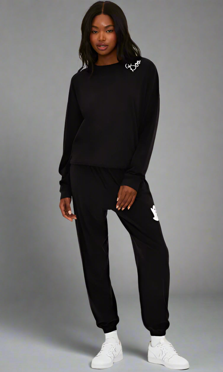 Person wearing a black tracksuit with brand logos on a white background