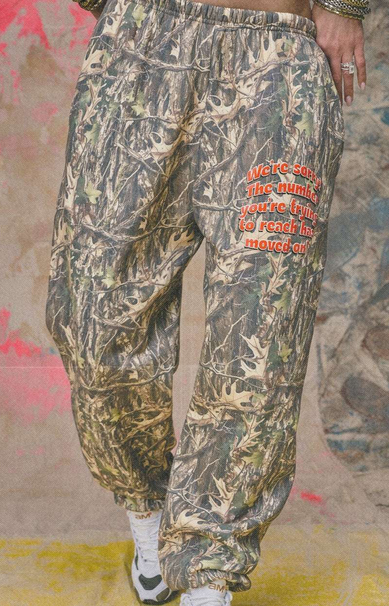 Camouflage pants with red text on a textured wall background
