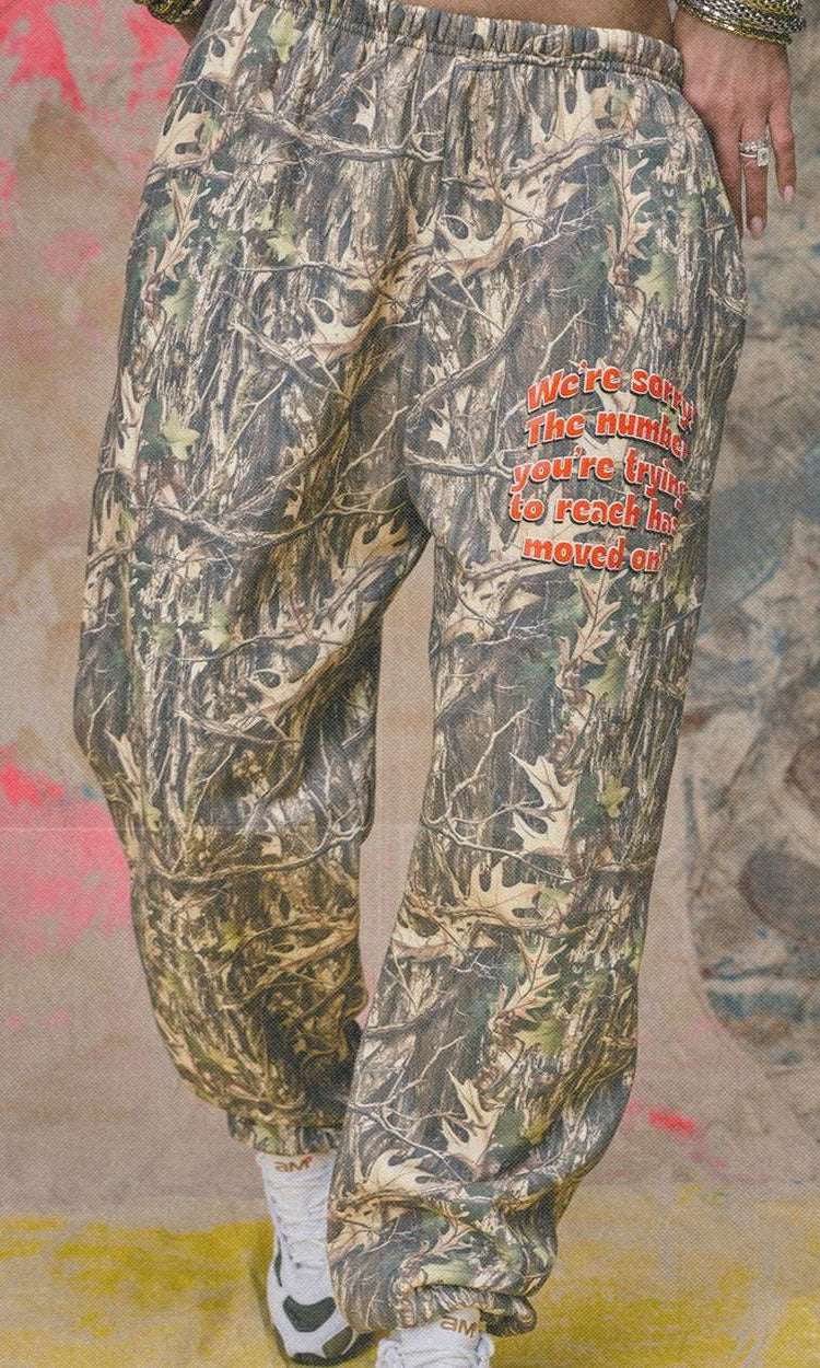 Camouflage pants with red text on a textured wall background