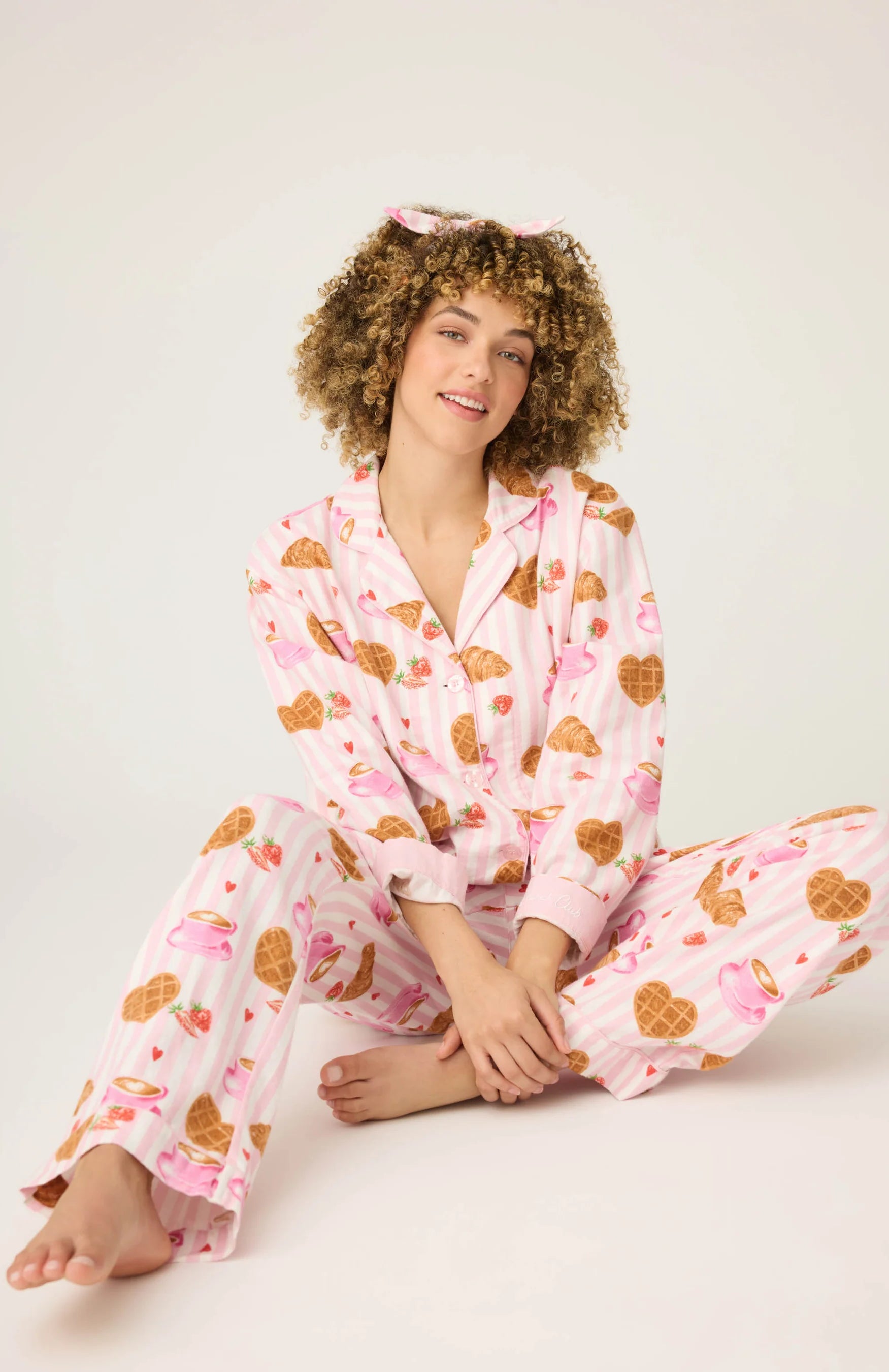 Woman wearing pink pajamas with heart patterns on a white background