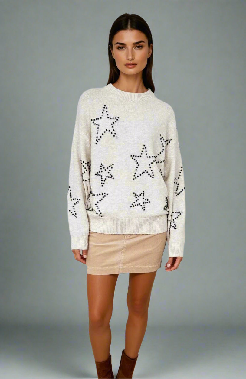 Woman wearing a cream sweater with star patterns on a white background