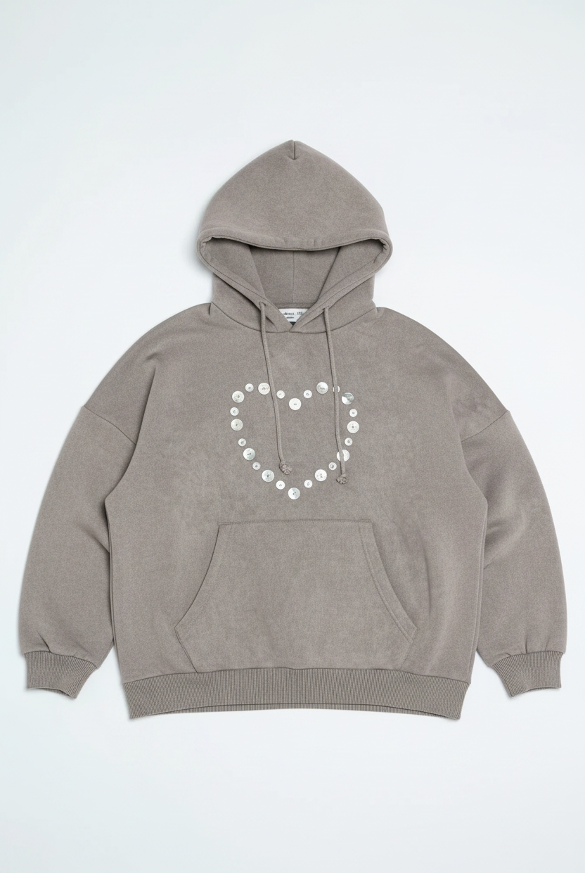 Woman wearing a gray hoodie and pants with decorative elements on a white background