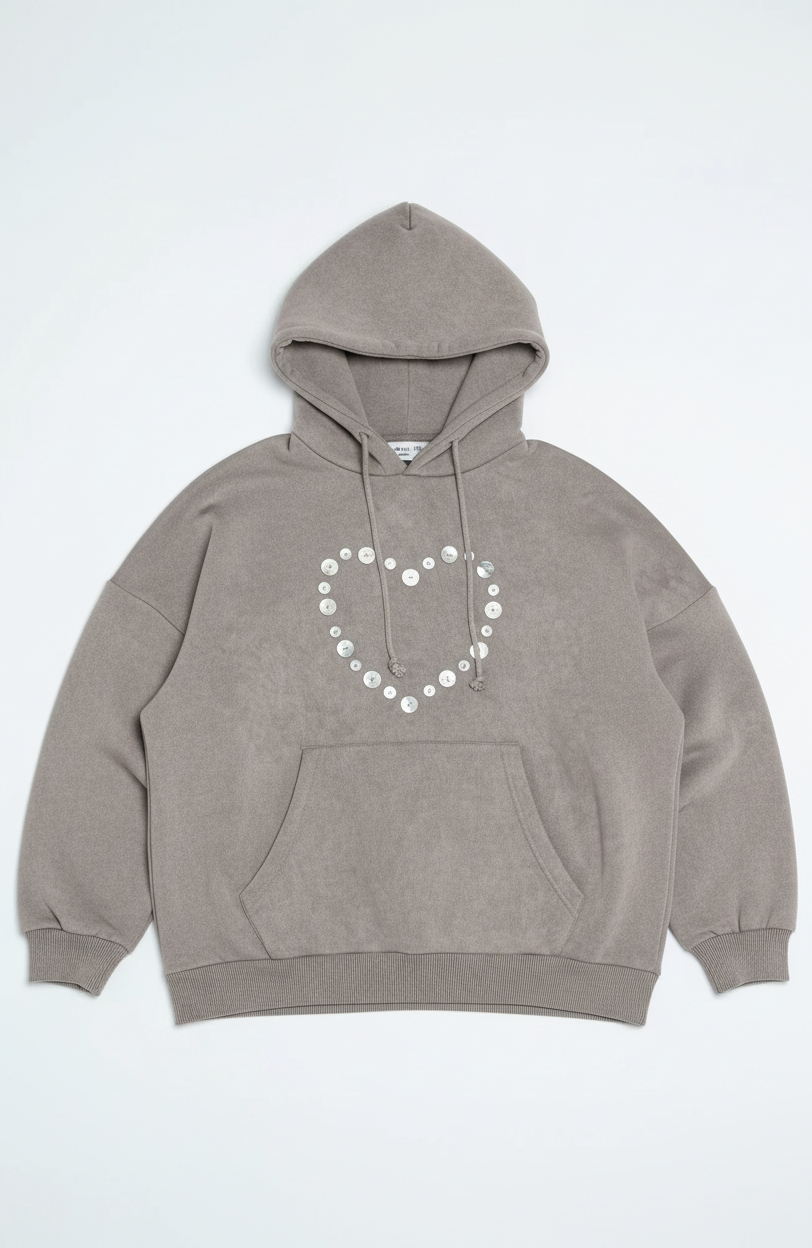 Woman wearing a gray hoodie and pants with decorative elements on a white background