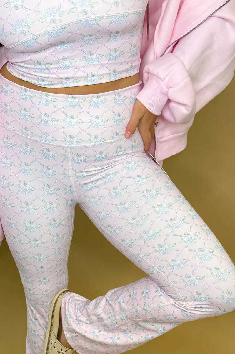 Person wearing a pastel floral outfit with a pink jacket on a neutral background