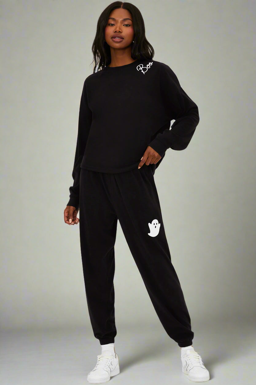 Person wearing a black tracksuit with a logo on a white background