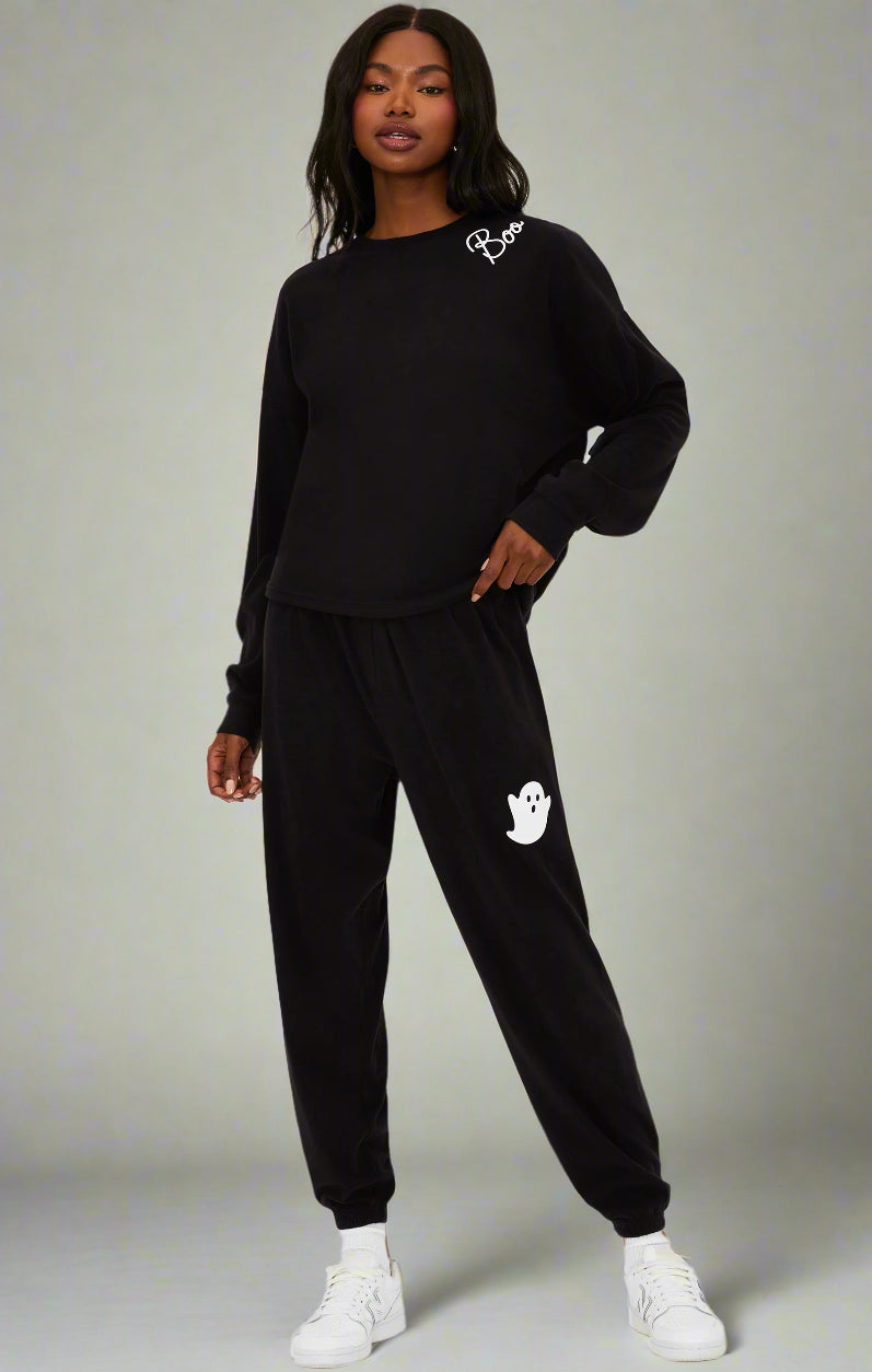 Person wearing a black tracksuit with a logo on a white background