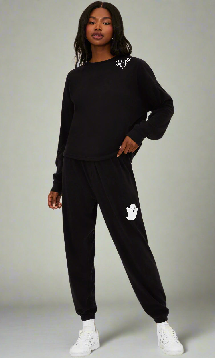 Person wearing a black tracksuit with a logo on a white background
