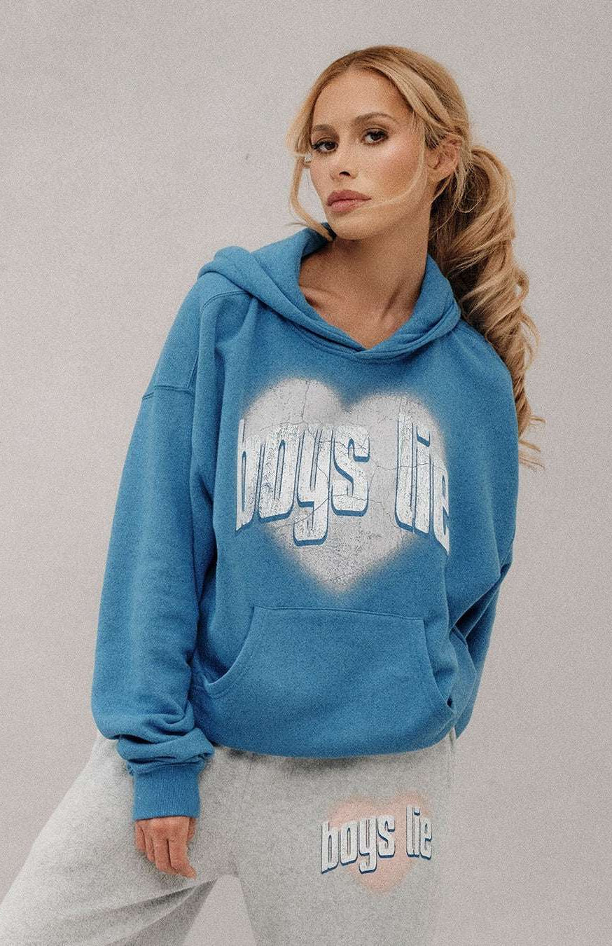 Woman wearing a blue hoodie with 'boys life' text, standing against a plain background