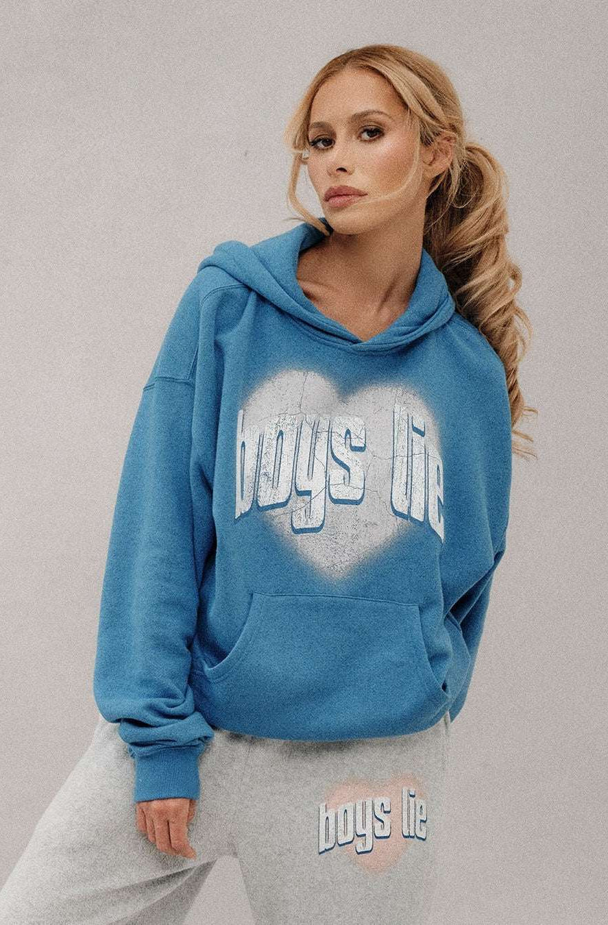 Woman wearing a blue hoodie with 'boys life' text, standing against a plain background