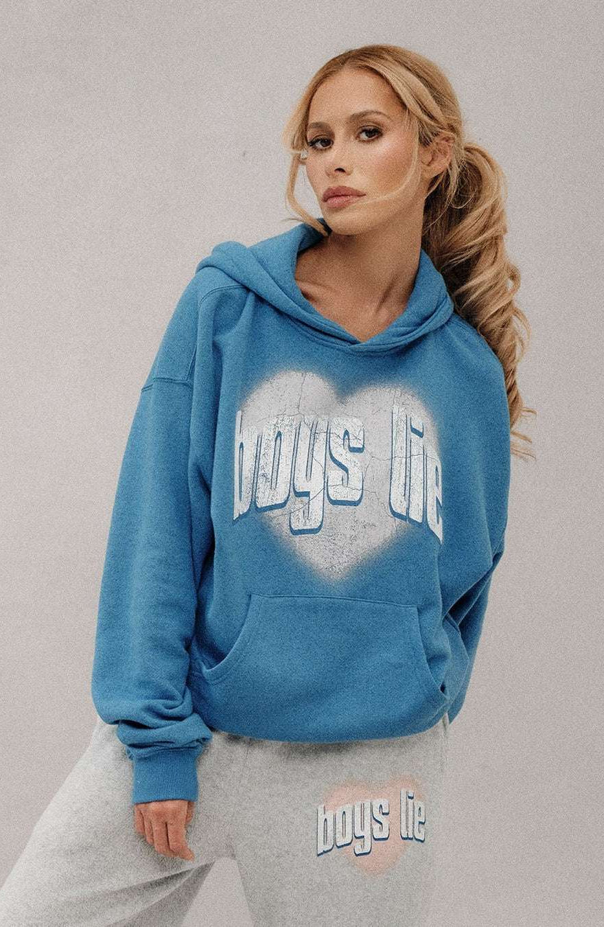 Woman wearing a blue hoodie with 'boys life' text, standing against a plain background