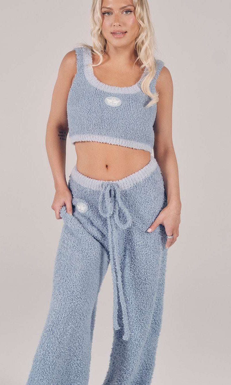 Woman wearing a light blue knitted outfit on a plain background