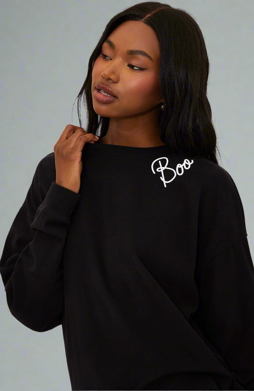 Person wearing a black sweatshirt with 'Boo' text on a white background