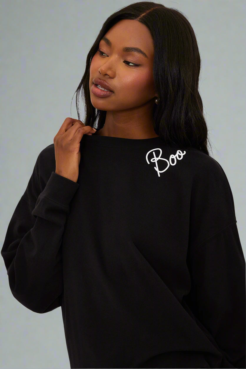 Person wearing a black sweatshirt with 'Boo' text on a white background
