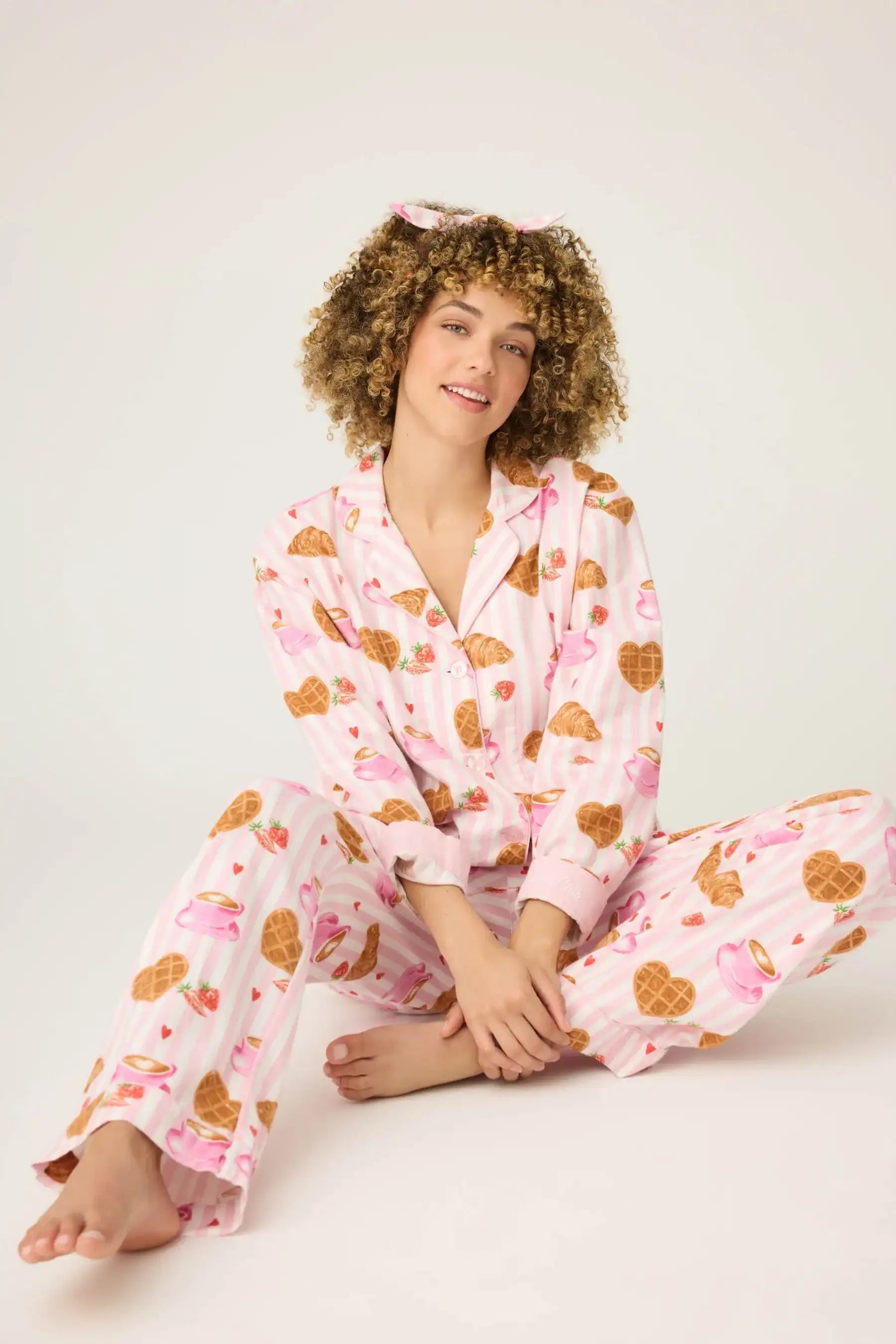 Woman wearing pink pajamas with heart patterns on a white background