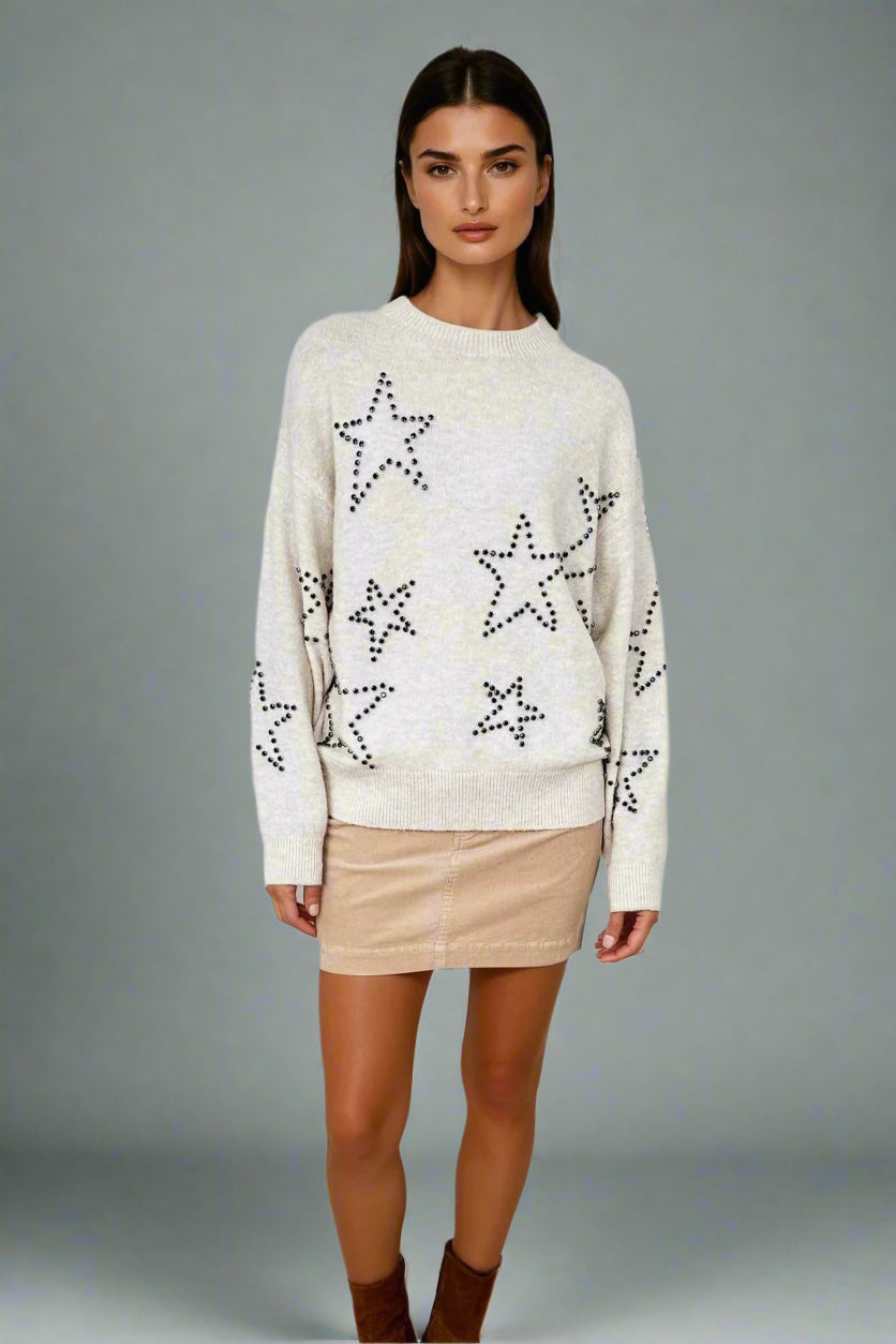 Woman wearing a cream sweater with star patterns on a white background