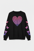 Woman wearing a black sweater with a pink and purple heart design on a white background