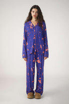 Woman wearing a blue pajama set with orange patterns on a white background