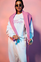 Person wearing a pink jacket, white t-shirt, and pants with a graphic design on a gradient background