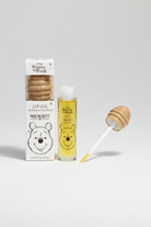 Lip oil with packaging featuring Winnie the Pooh design on a gray background