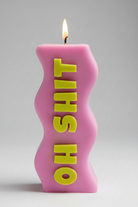 Pink candle with yellow text on a gray background