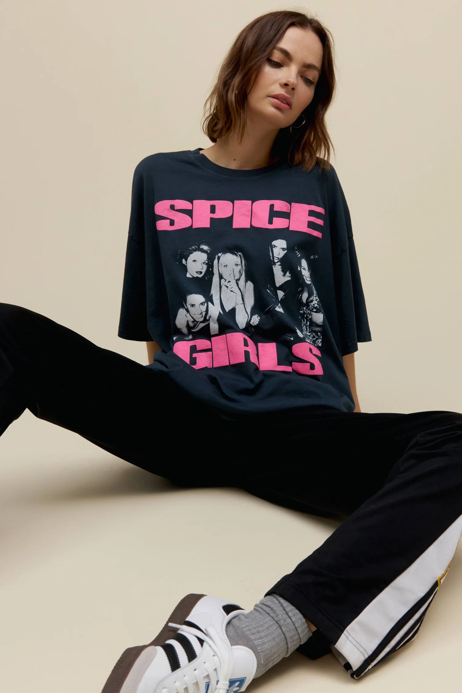 Woman wearing a Spice Girls t-shirt sitting on a beige surface