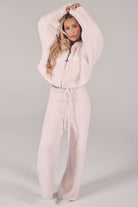 Woman wearing a light pink fleece tracksuit on a plain background